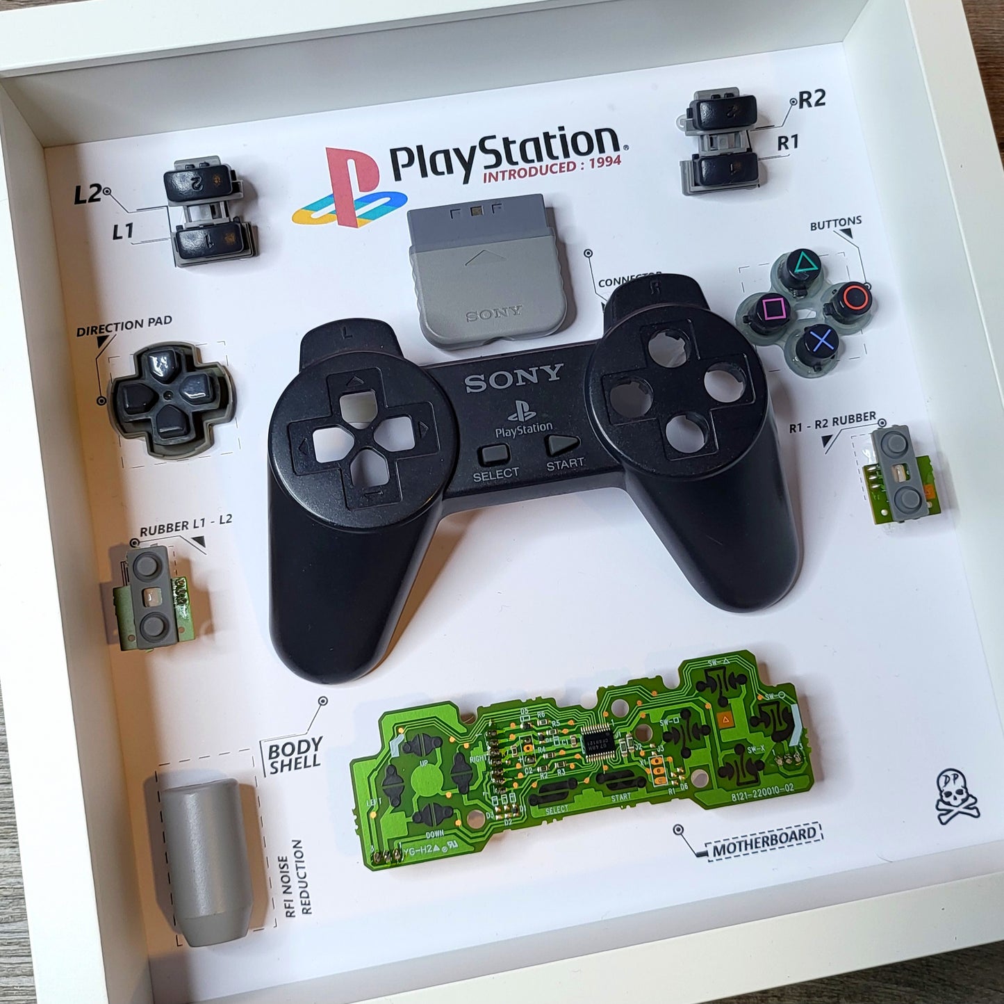 Shadow Box 10x10 with wood frame and polycarbonate glass for wall and Tabletop containing a disassembled controller for Playstation and Nintendo