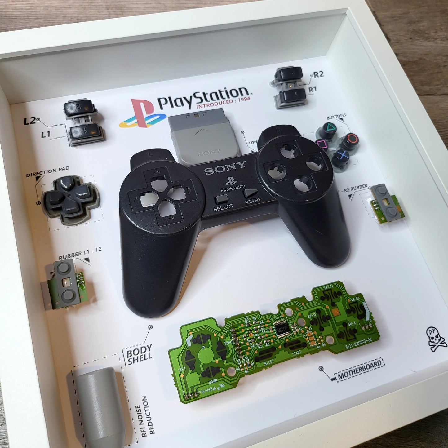 Shadow Box 10x10 with wood frame and polycarbonate glass for wall and Tabletop containing a disassembled controller for Playstation and Nintendo