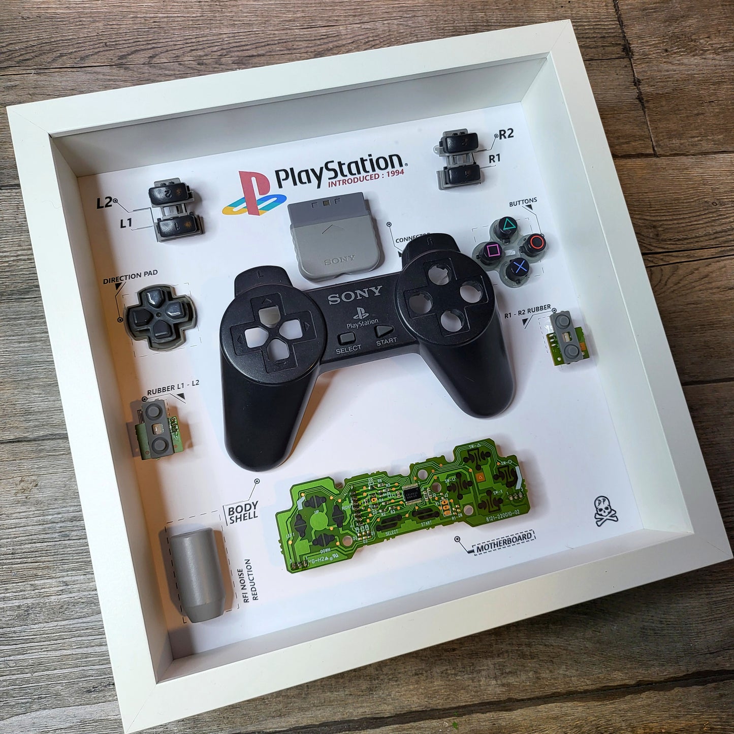Shadow Box 10x10 with wood frame and polycarbonate glass for wall and Tabletop containing a disassembled controller for Playstation and Nintendo