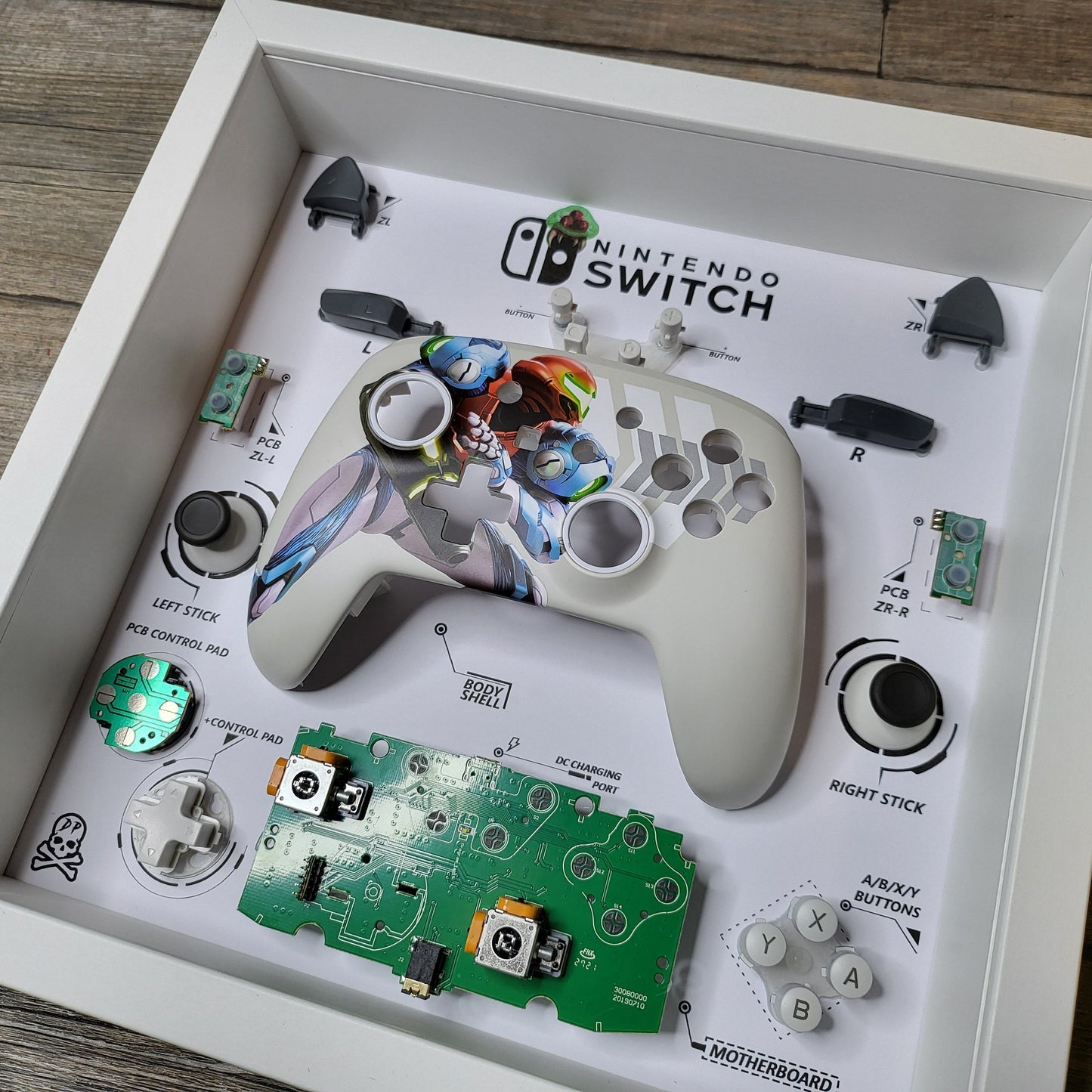 Shadow Box 10x10 with wood frame and polycarbonate glass for wall and Tabletop containing a disassembled controller for Playstation and Nintendo