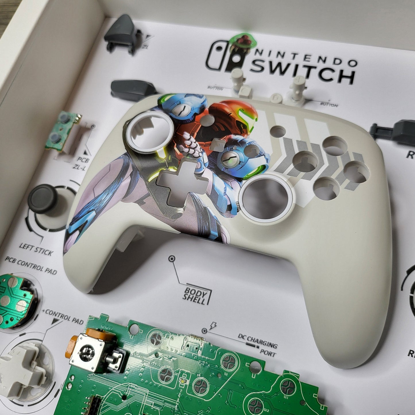 Shadow Box 10x10 with wood frame and polycarbonate glass for wall and Tabletop containing a disassembled controller for Playstation and Nintendo