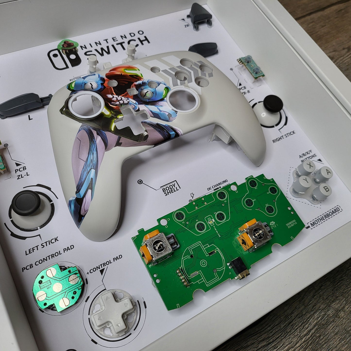 Shadow Box 10x10 with wood frame and polycarbonate glass for wall and Tabletop containing a disassembled controller for Playstation and Nintendo