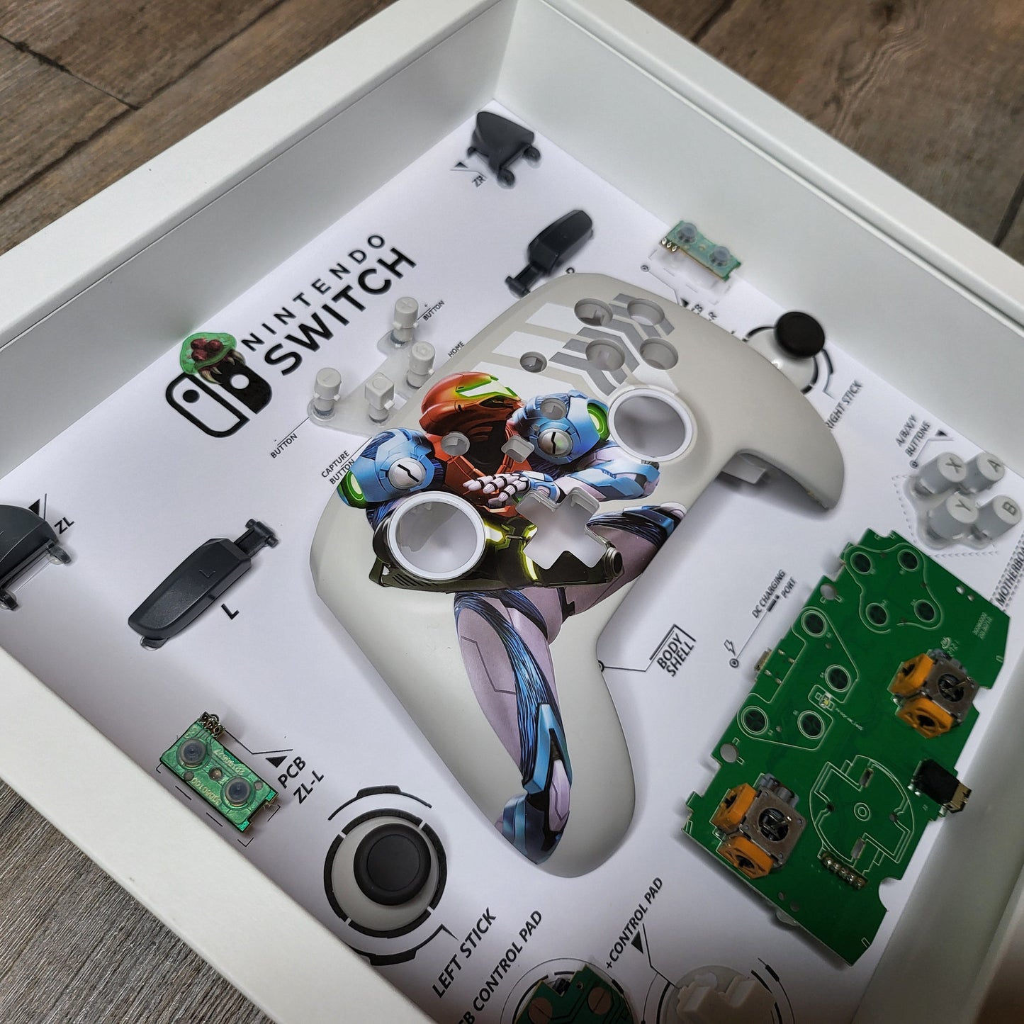 Shadow Box 10x10 with wood frame and polycarbonate glass for wall and Tabletop containing a disassembled controller for Playstation and Nintendo
