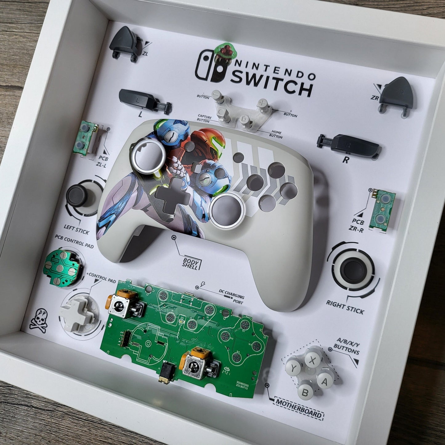 Shadow Box 10x10 with wood frame and polycarbonate glass for wall and Tabletop containing a disassembled controller for Playstation and Nintendo