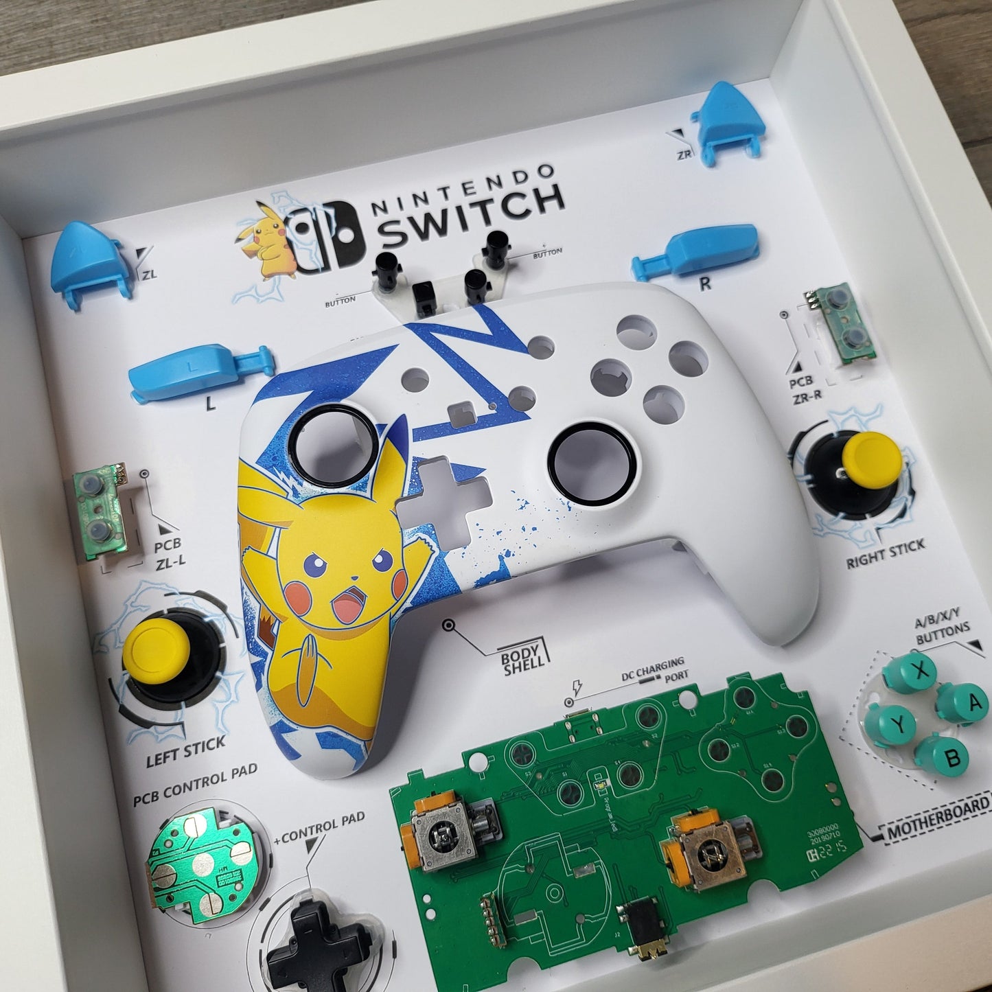 Shadow Box 10x10 with wood frame and polycarbonate glass for wall and Tabletop containing a disassembled controller for Playstation and Nintendo