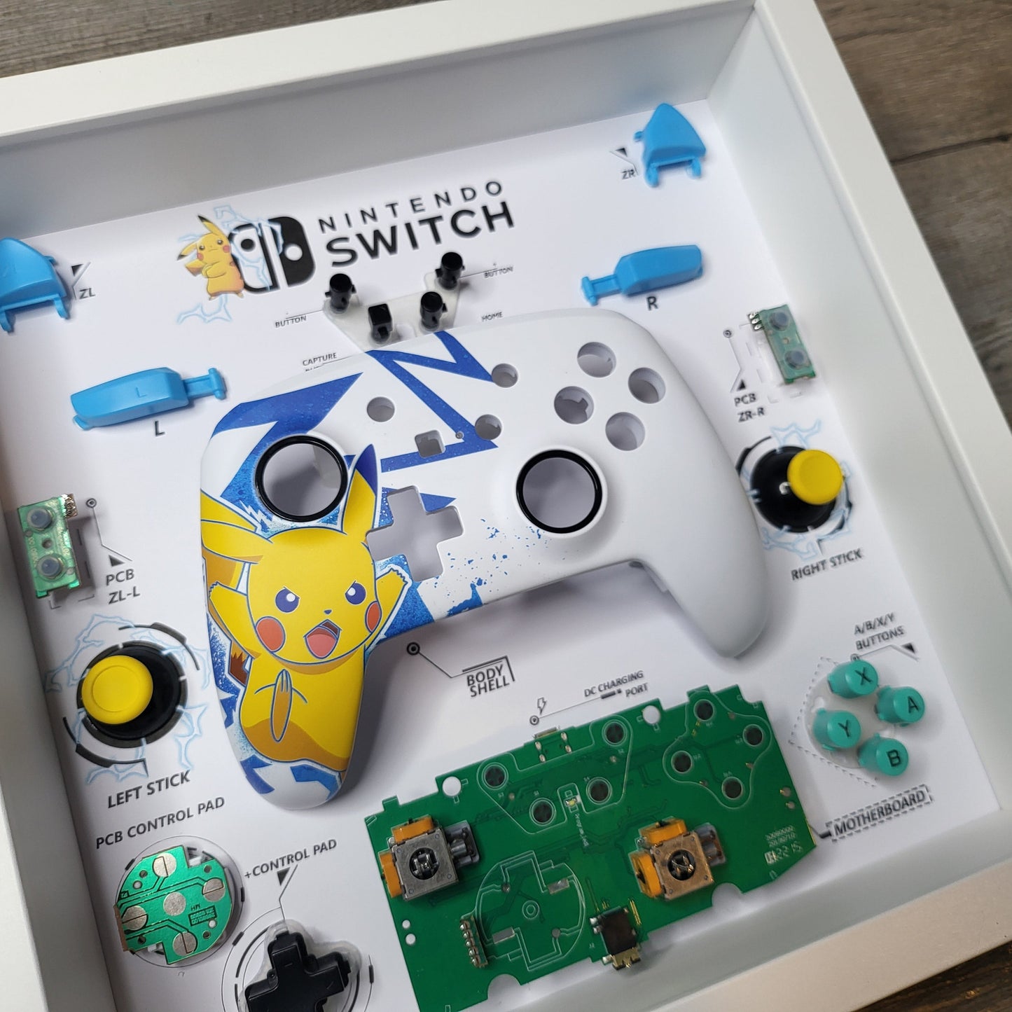 Shadow Box 10x10 with wood frame and polycarbonate glass for wall and Tabletop containing a disassembled controller for Playstation and Nintendo