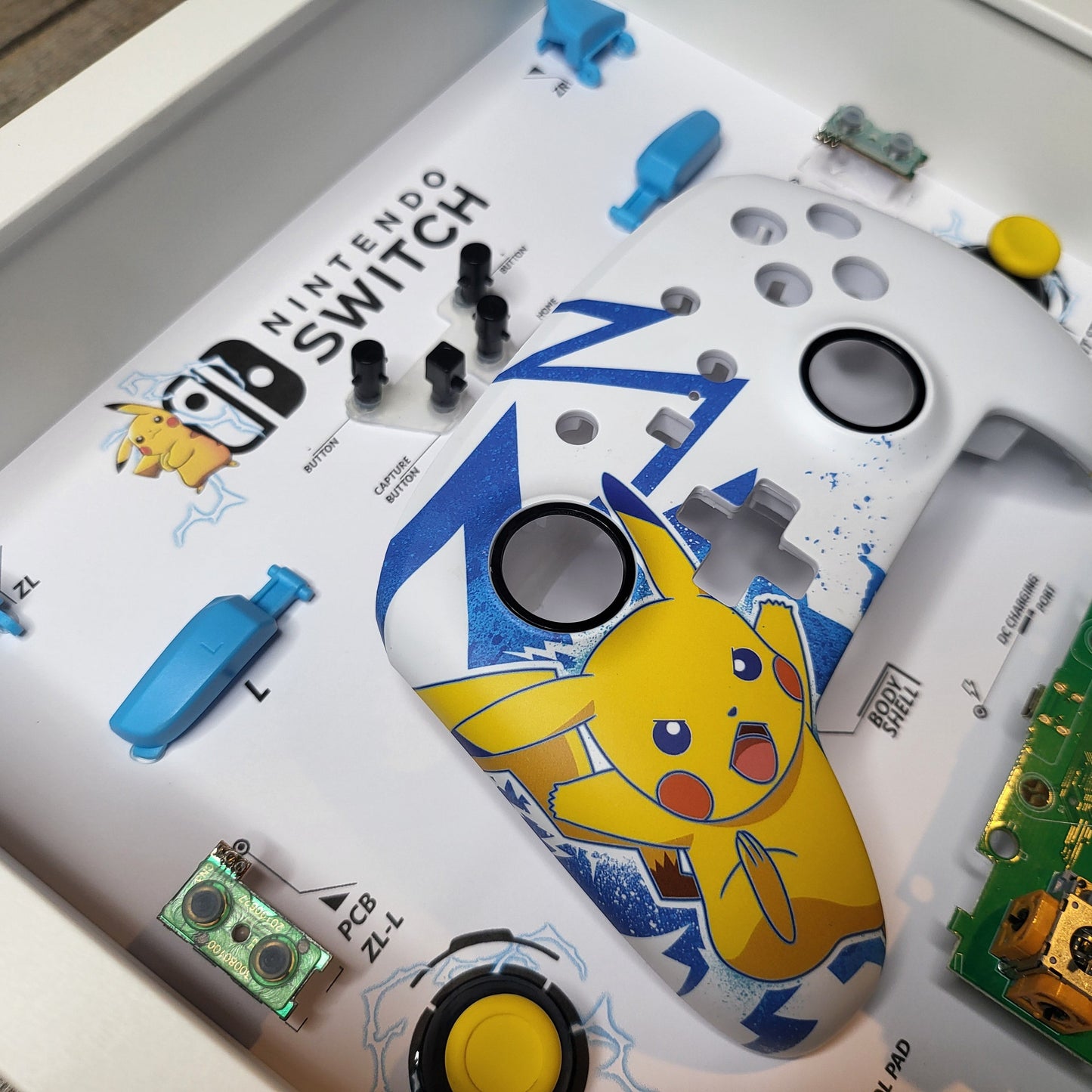Shadow Box 10x10 with wood frame and polycarbonate glass for wall and Tabletop containing a disassembled controller for Playstation and Nintendo