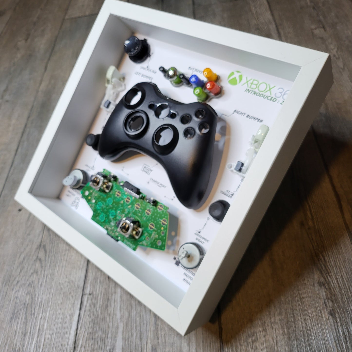 Shadow Box 10x10 with wood frame and polycarbonate glass for wall and Tabletop containing a disassembled controller for Playstation and Nintendo