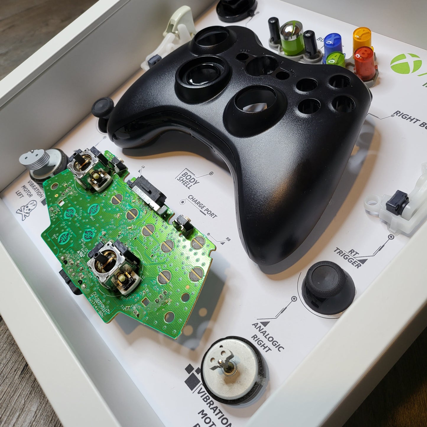 Shadow Box 10x10 with wood frame and polycarbonate glass for wall and Tabletop containing a disassembled controller for Playstation and Nintendo