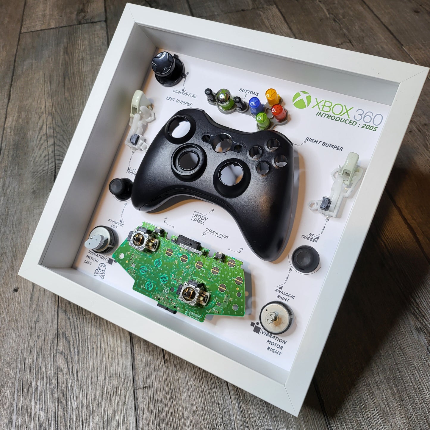 Shadow Box 10x10 with wood frame and polycarbonate glass for wall and Tabletop containing a disassembled controller for Playstation and Nintendo