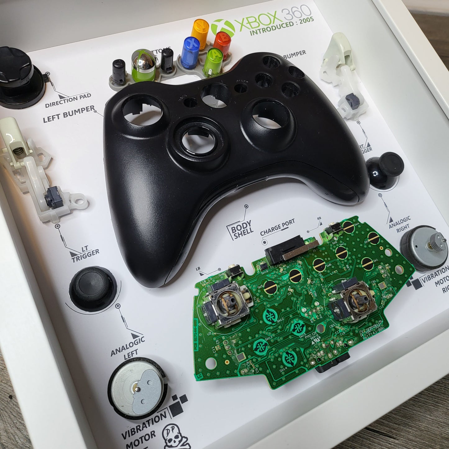Shadow Box 10x10 with wood frame and polycarbonate glass for wall and Tabletop containing a disassembled controller for Playstation and Nintendo