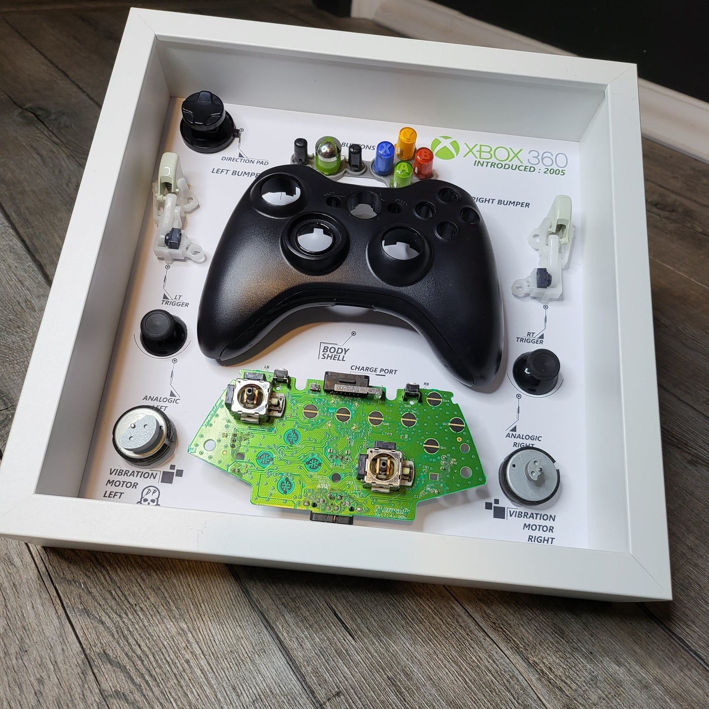 Shadow Box 10x10 with wood frame and polycarbonate glass for wall and Tabletop containing a disassembled controller for Playstation and Nintendo