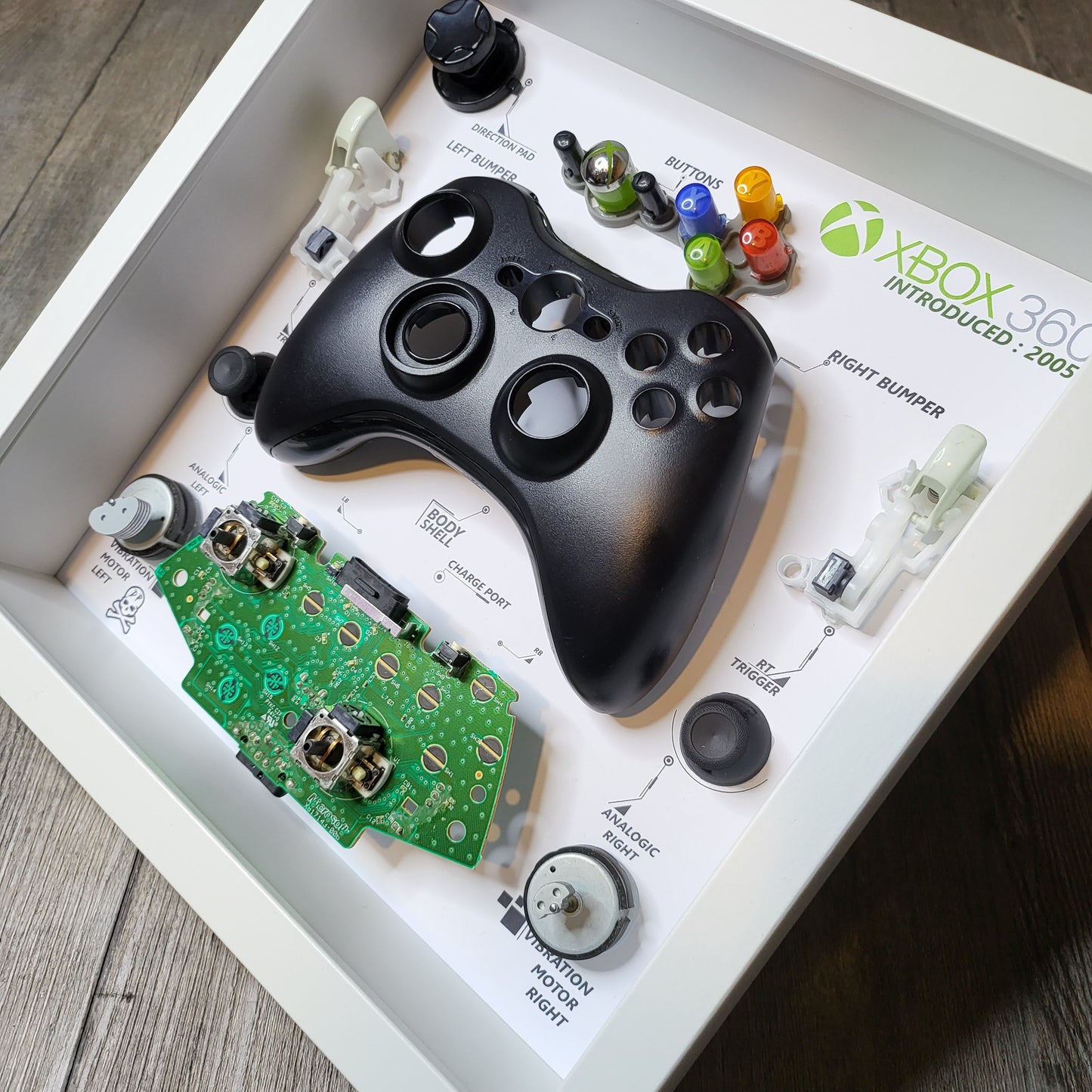 Shadow Box 10x10 with wood frame and polycarbonate glass for wall and Tabletop containing a disassembled controller for Playstation and Nintendo