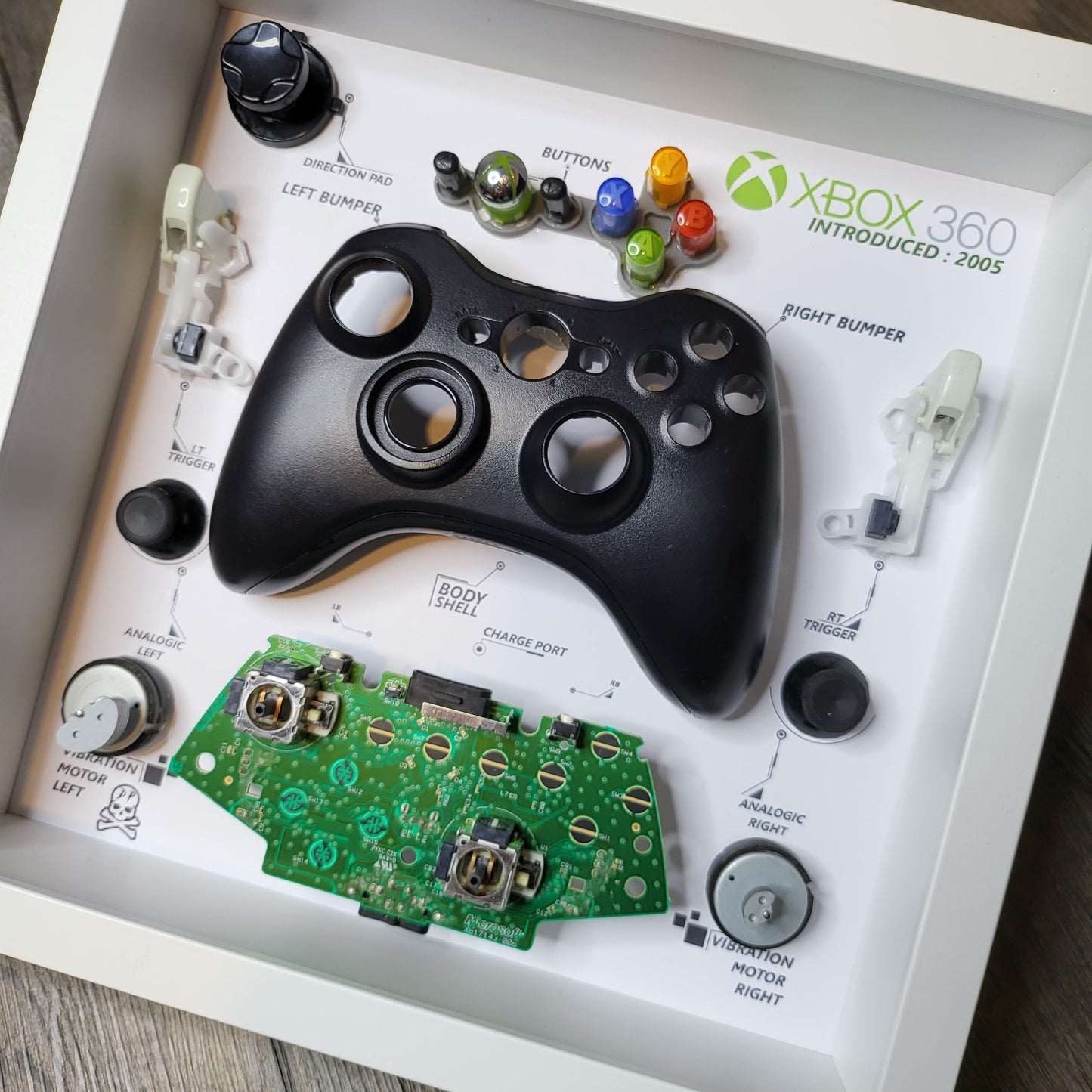 Shadow Box 10x10 with wood frame and polycarbonate glass for wall and Tabletop containing a disassembled controller for Playstation and Nintendo