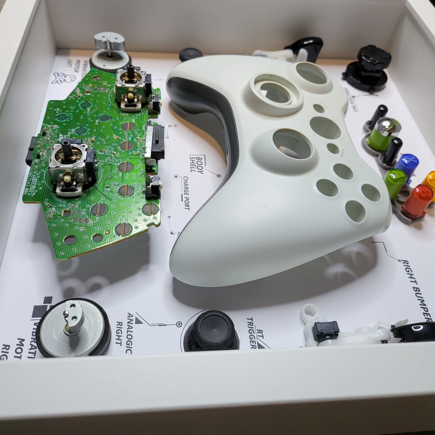 Shadow Box 10x10 with wood frame and polycarbonate glass for wall and Tabletop containing a disassembled controller for Playstation and Nintendo