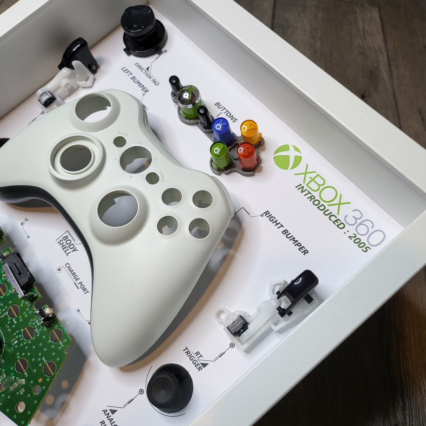 Shadow Box 10x10 with wood frame and polycarbonate glass for wall and Tabletop containing a disassembled controller for Playstation and Nintendo