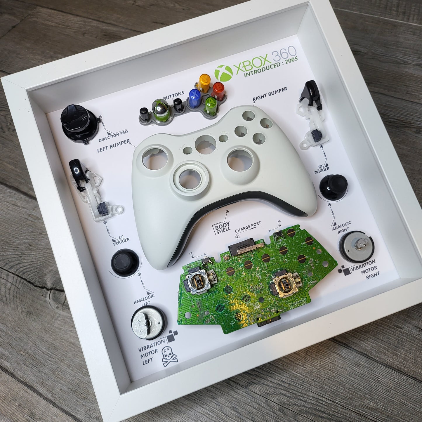 Shadow Box 10x10 with wood frame and polycarbonate glass for wall and Tabletop containing a disassembled controller for Playstation and Nintendo