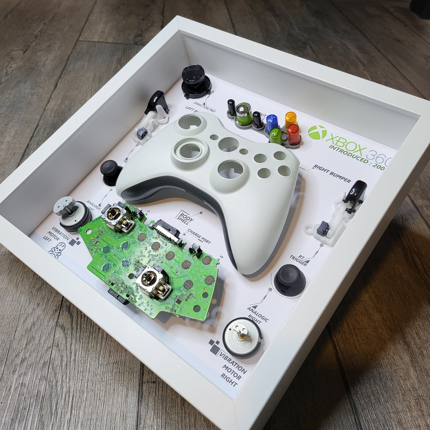 Shadow Box 10x10 with wood frame and polycarbonate glass for wall and Tabletop containing a disassembled controller for Playstation and Nintendo