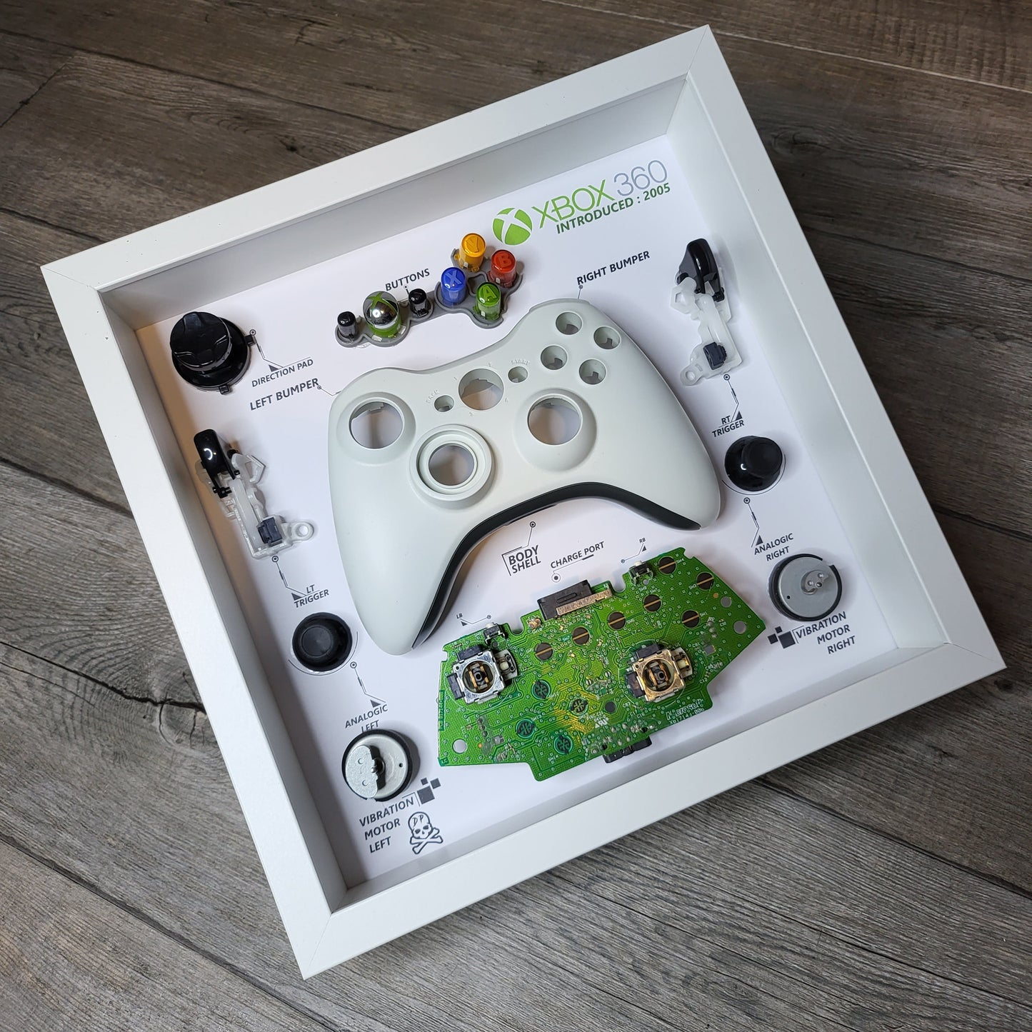 Shadow Box 10x10 with wood frame and polycarbonate glass for wall and Tabletop containing a disassembled controller for Playstation and Nintendo