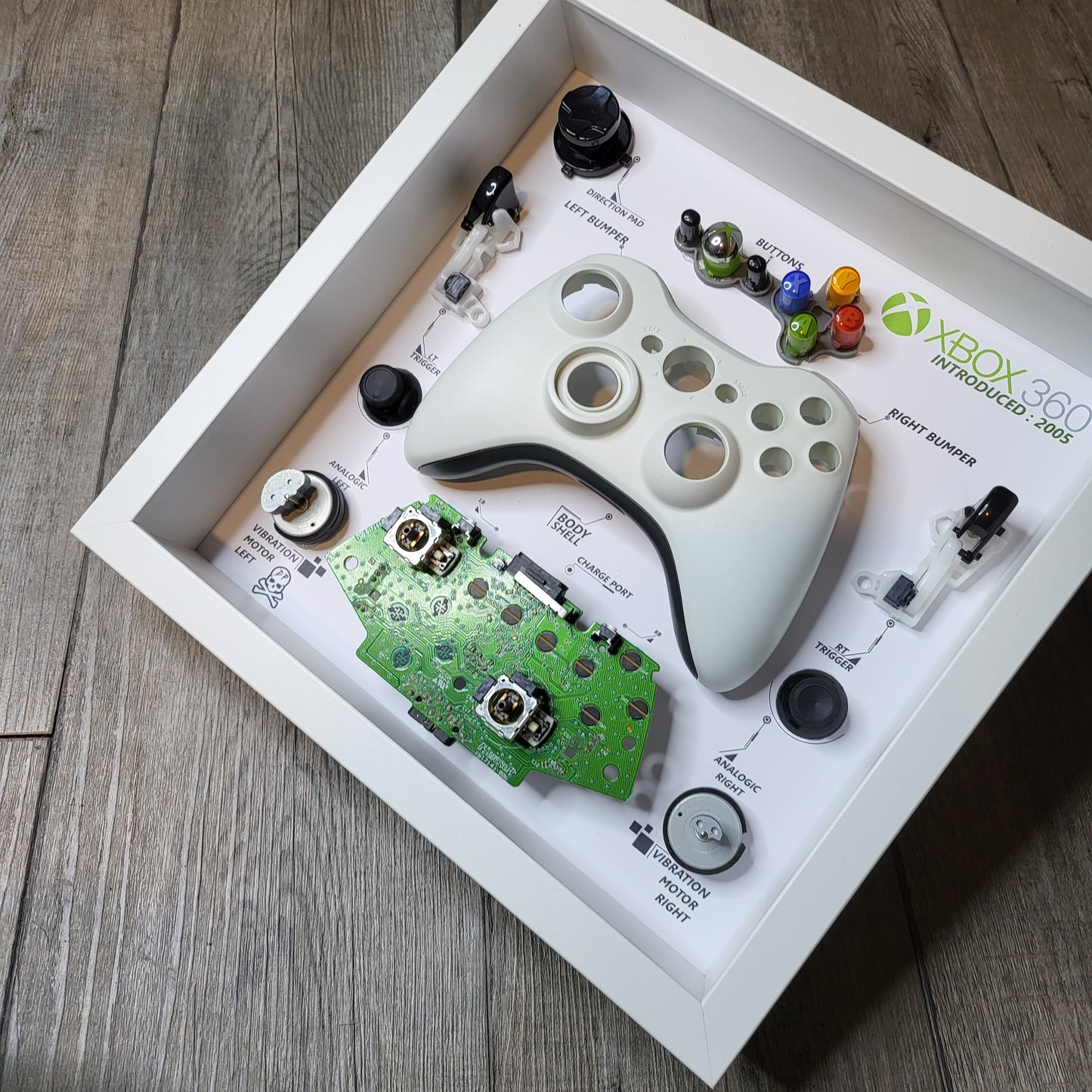 Shadow Box 10x10 with wood frame and polycarbonate glass for wall and Tabletop containing a disassembled controller for Playstation and Nintendo