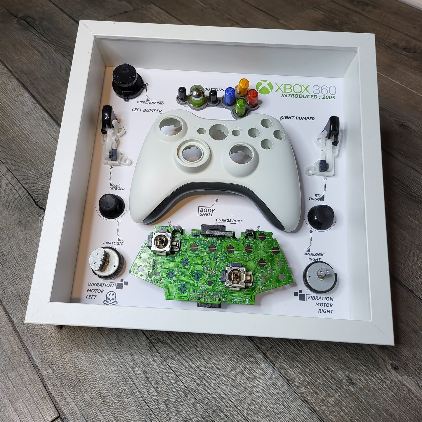 Shadow Box 10x10 with wood frame and polycarbonate glass for wall and Tabletop containing a disassembled controller for Playstation and Nintendo
