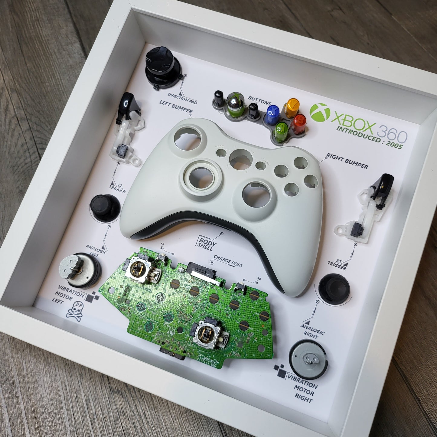 Shadow Box 10x10 with wood frame and polycarbonate glass for wall and Tabletop containing a disassembled controller for Playstation and Nintendo