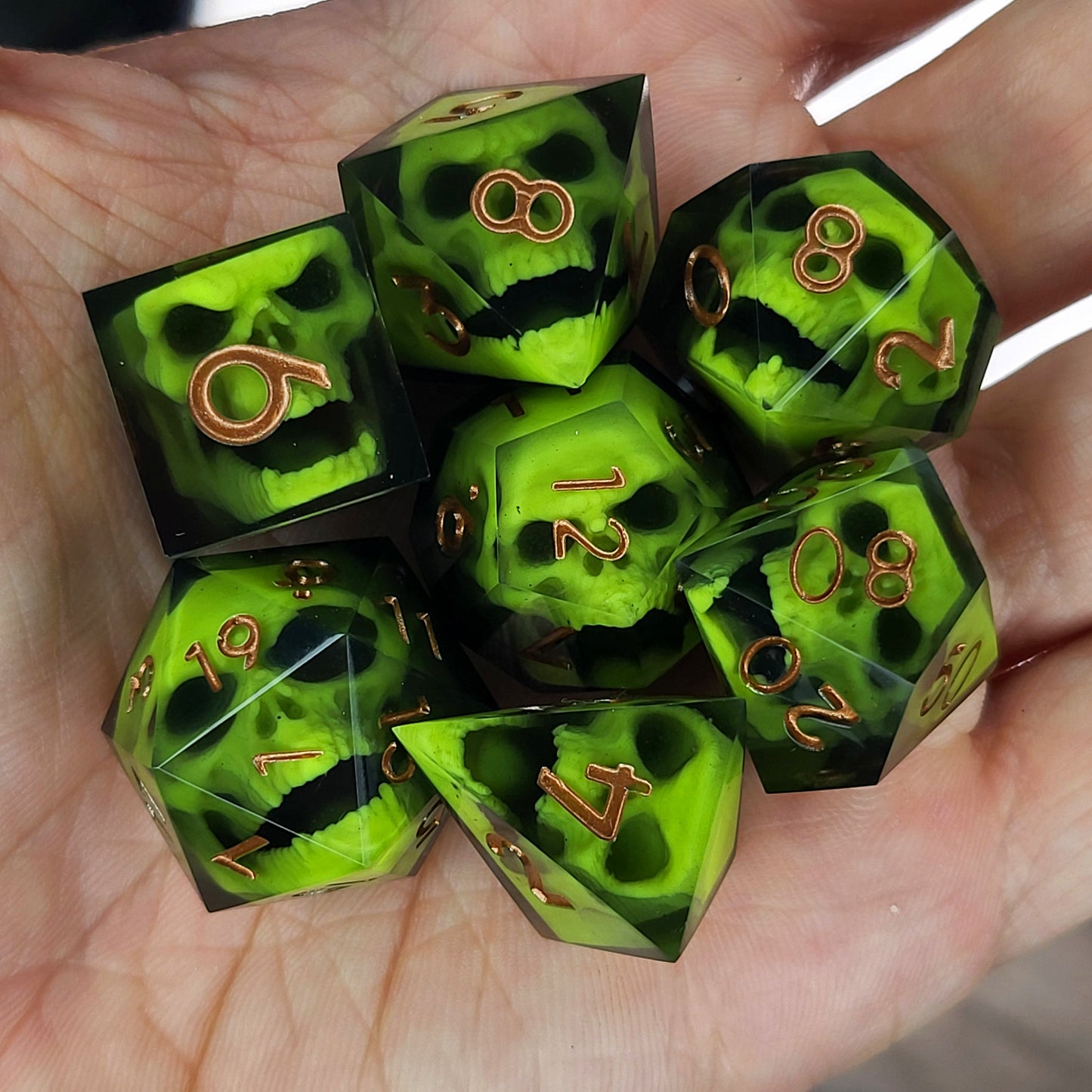 Black resin dice set featuring neon green undead skulls and metallic bronze numbers, handcrafted RPG dice for DnD and tabletop fantasy games
