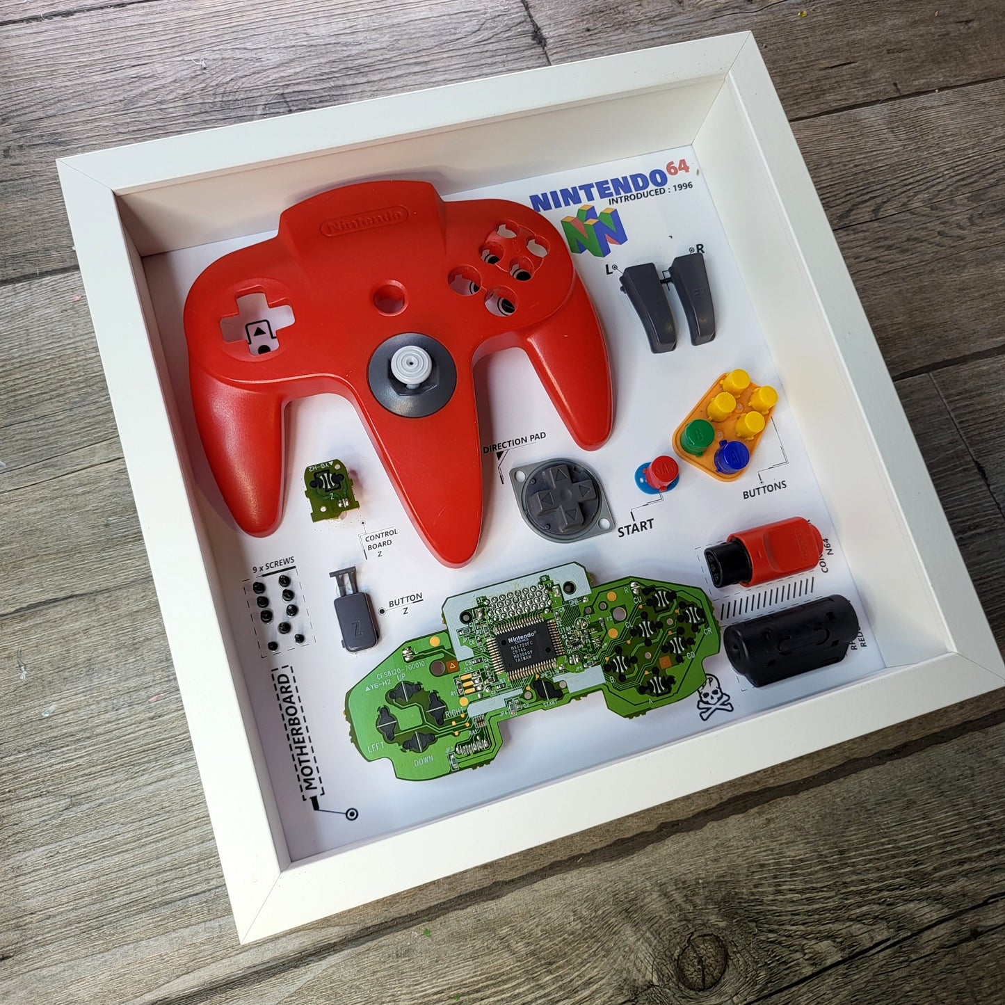 Shadow Box 10x10 with wood frame and polycarbonate glass for wall and Tabletop containing a disassembled controller for Playstation and Nintendo