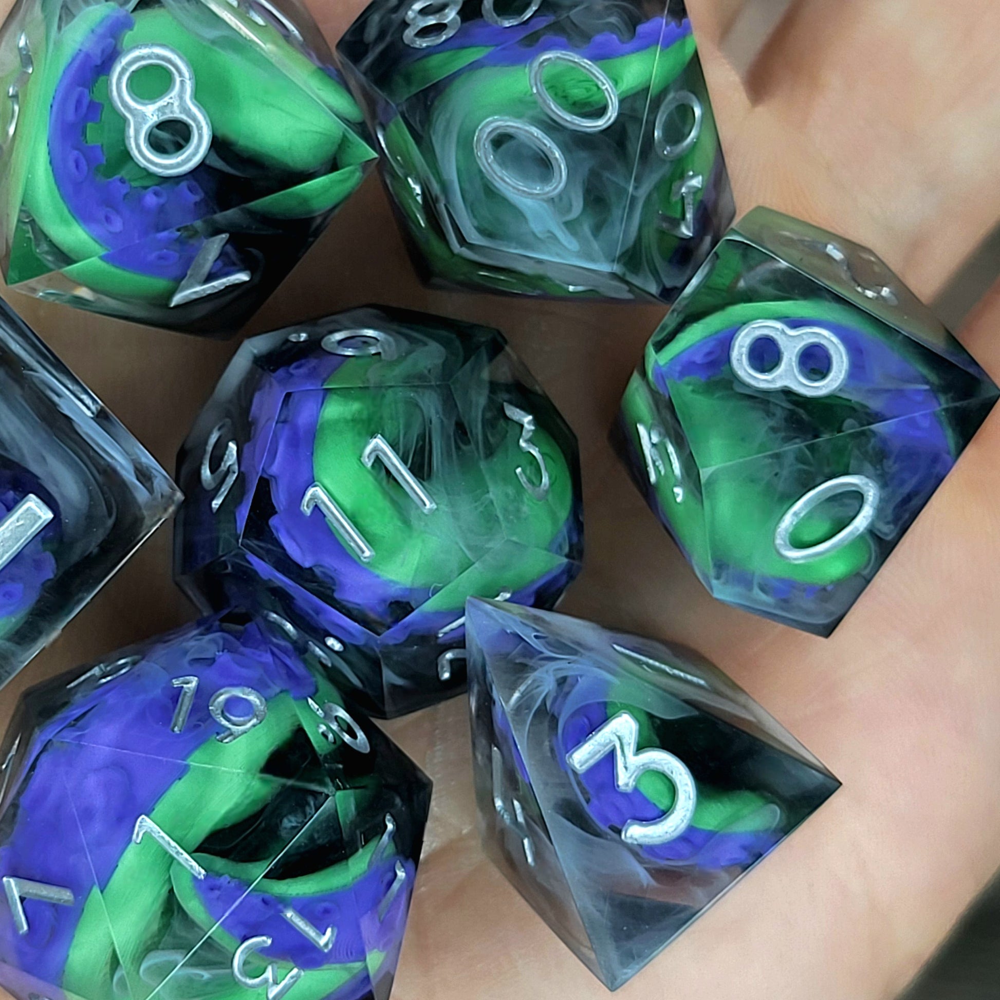 Handcrafted sharp edge resin dice featuring eerie green and purple tentacles suspended in dark transparent resin, surrounded by ghostly white mist and finished with metallic silver numbers