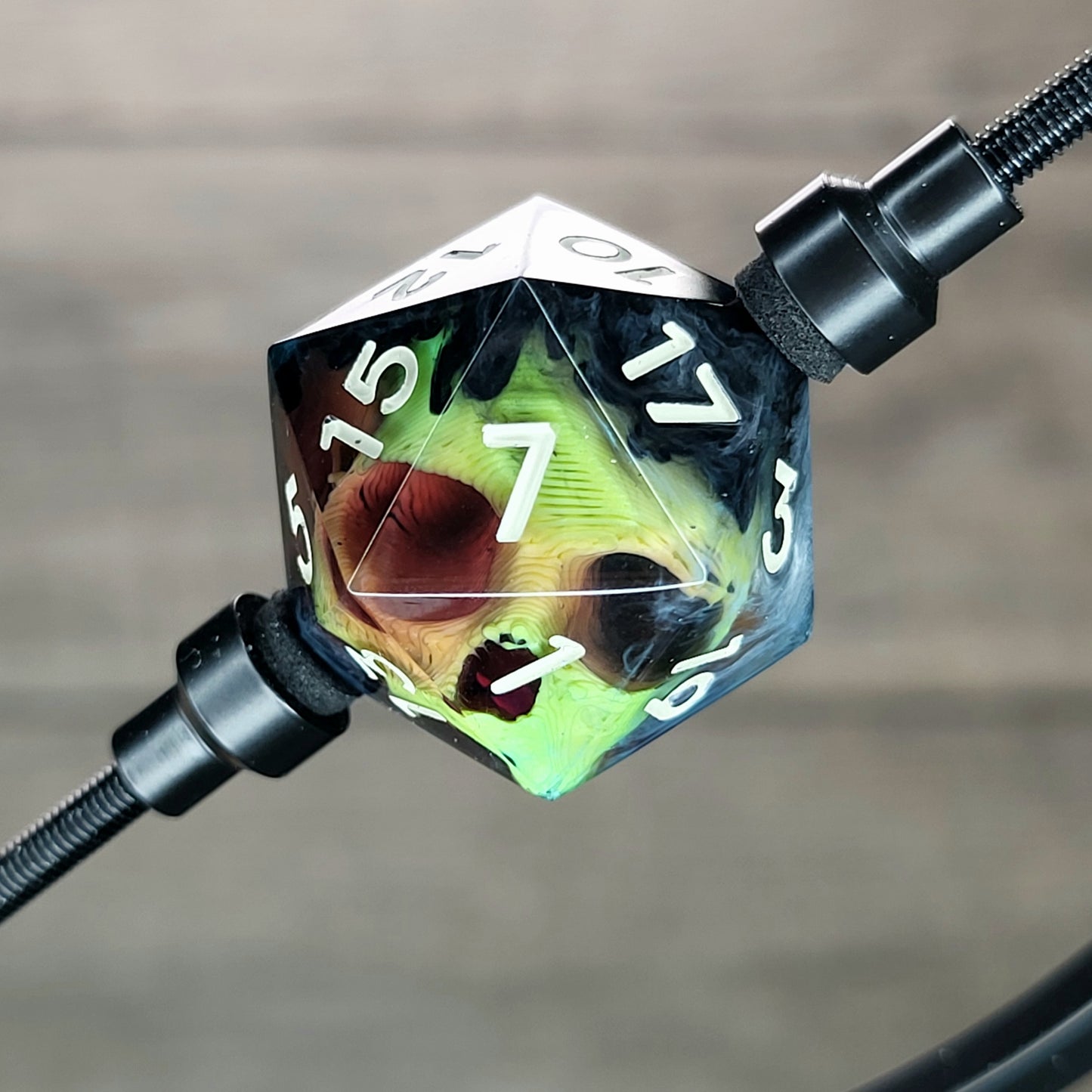 This is a single set of one D20 DnD die with a yellow skull inside , black and white resin and gold and grey number