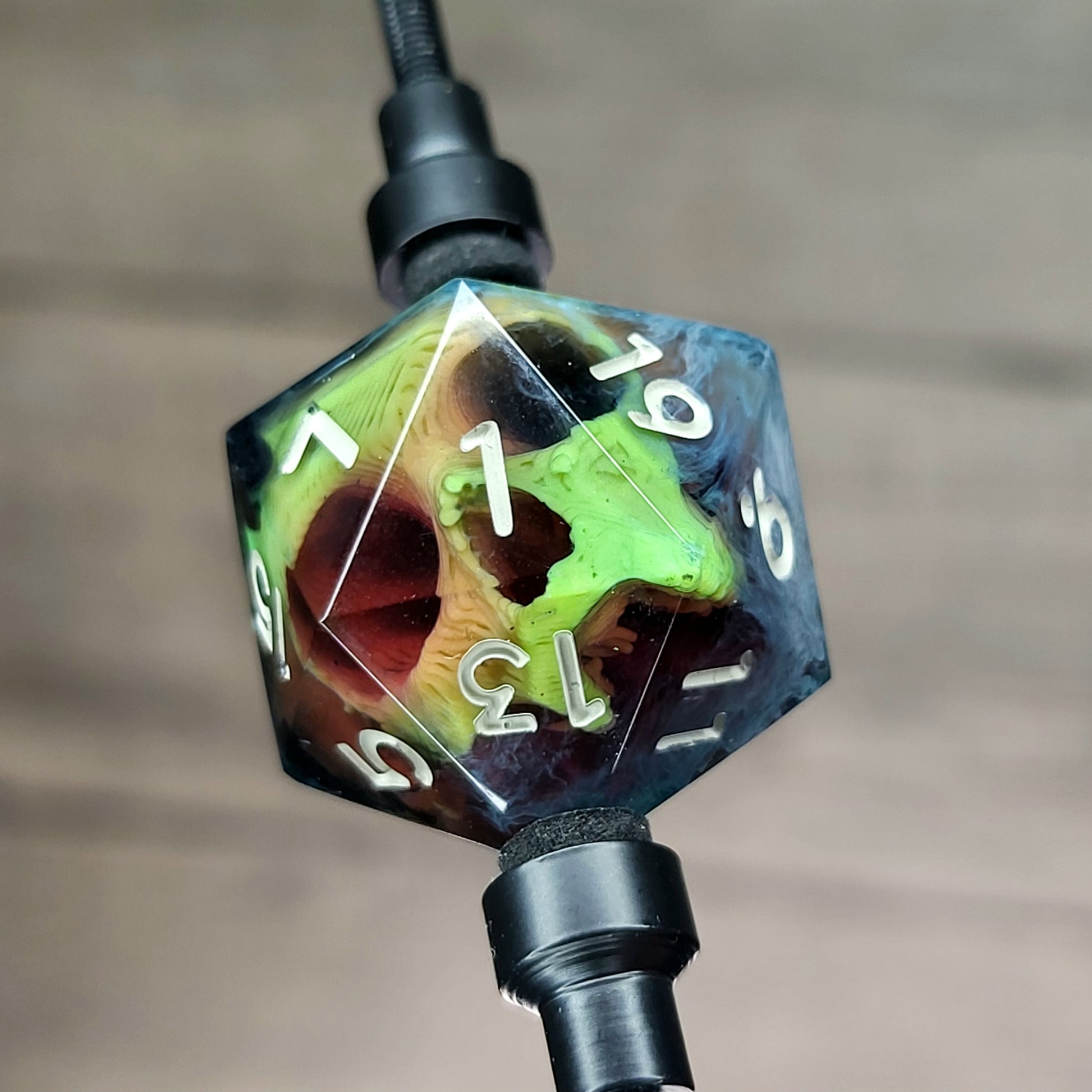 This is a single set of one D20 DnD die with a yellow skull inside , black and white resin and gold and grey number