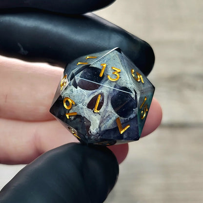 This is a single set of one D20 DnD die with a grey stone skull inside , black resin and gold numbers