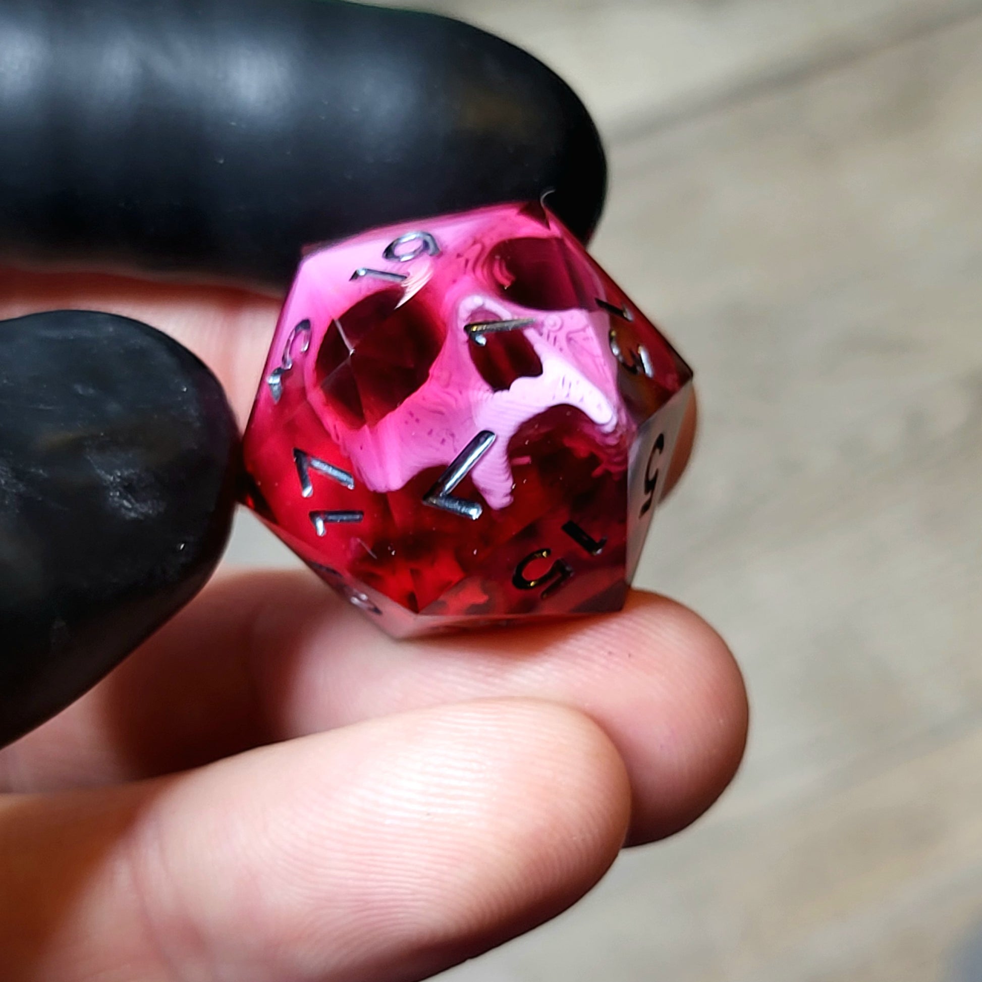 This is a single set of one D20 DND die with a pink skull inside ,red resin and black silver numbers