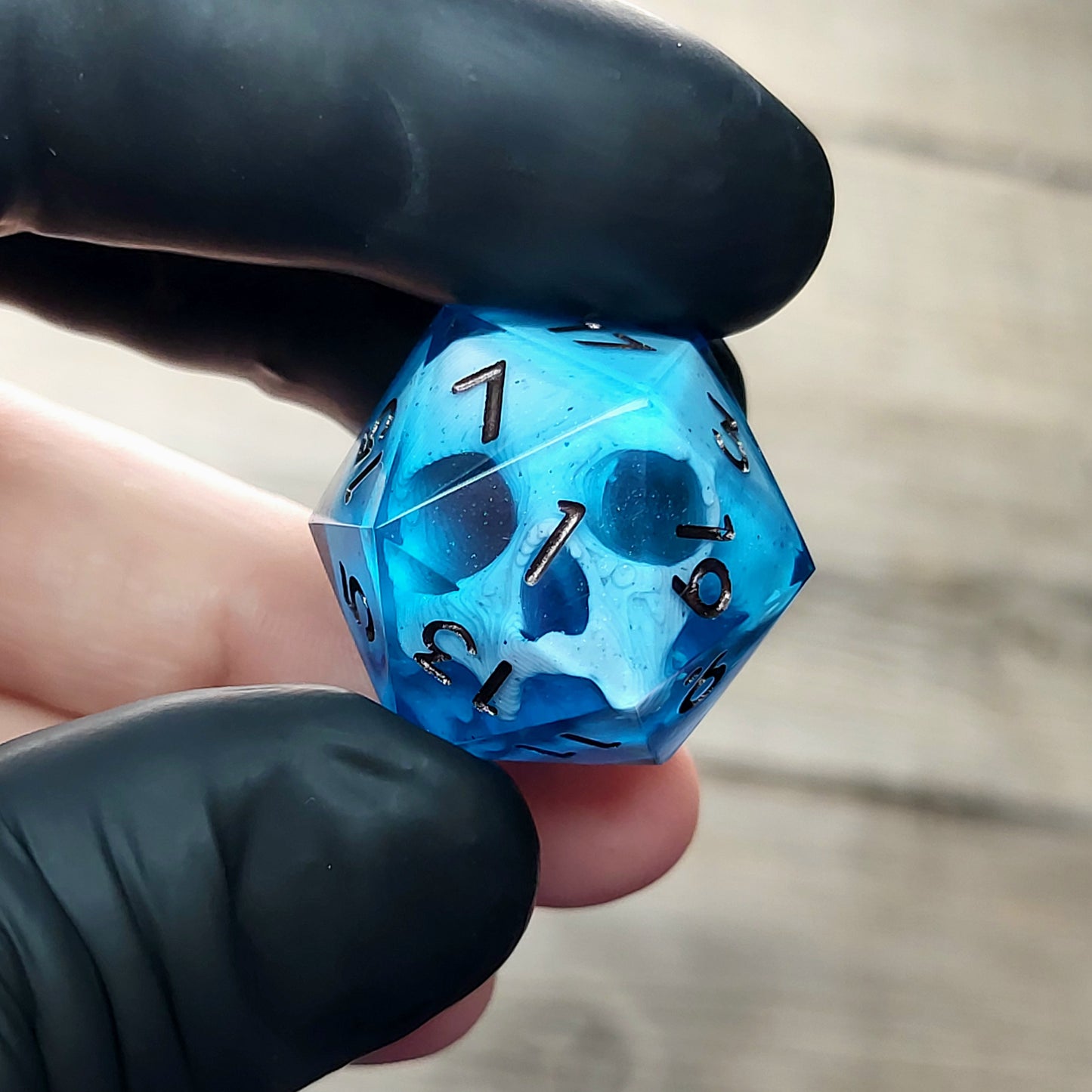 This is a single set of one D20 DnD die with a white skull inside ,blue resin and metal dark numbers