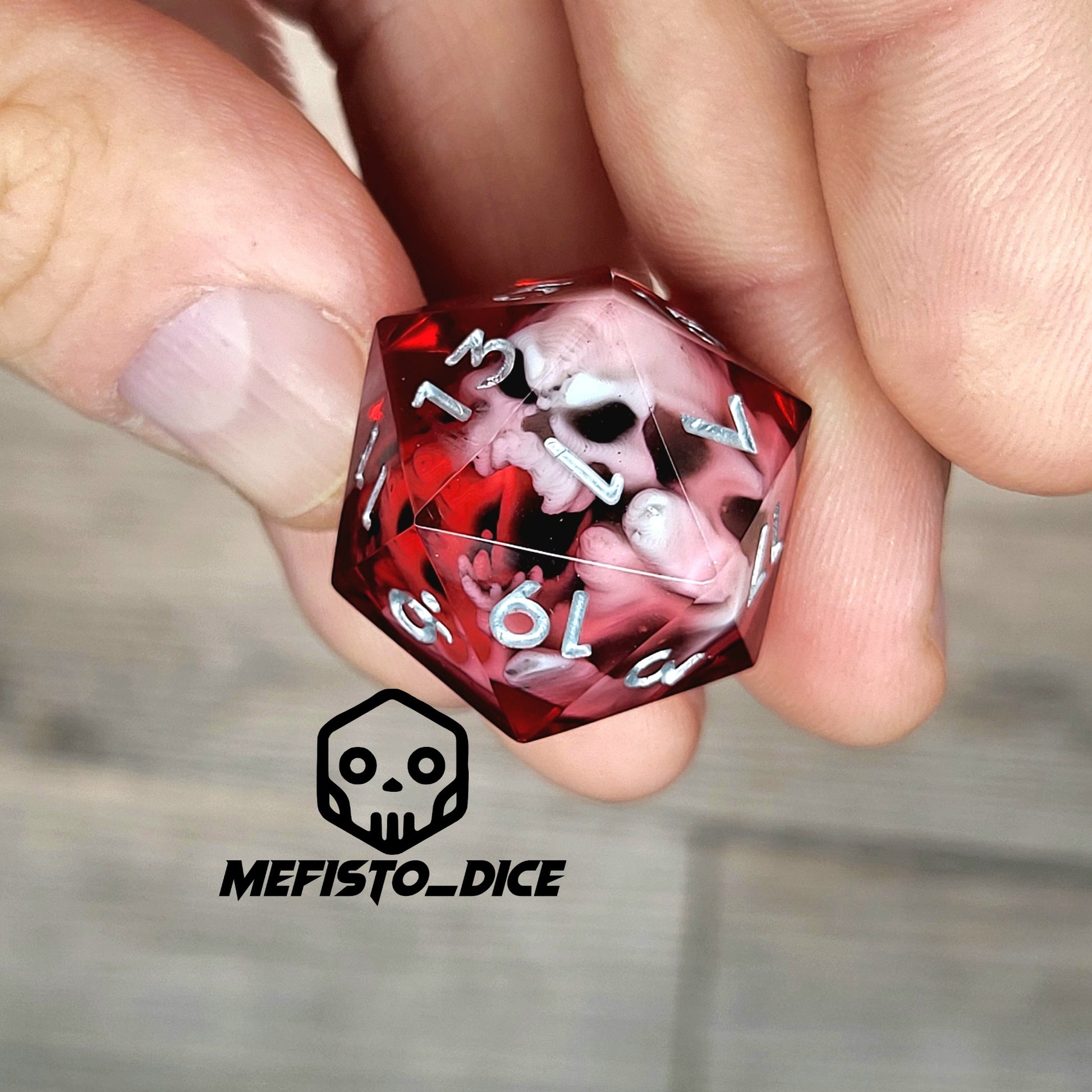 Red resin DnD dice with white skull inside and silver engraved numbers