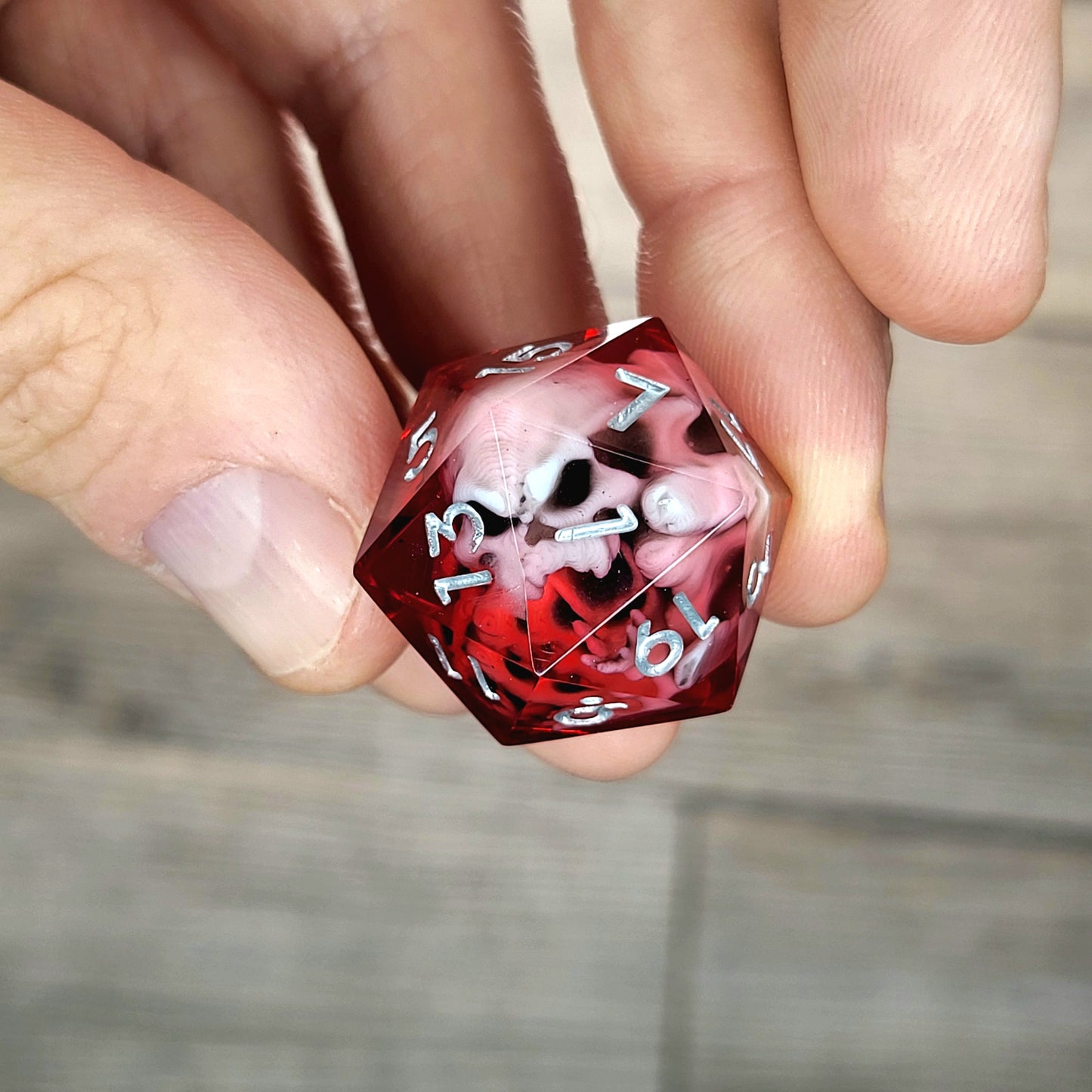 Red resin DnD dice with white skull inside and silver engraved numbers