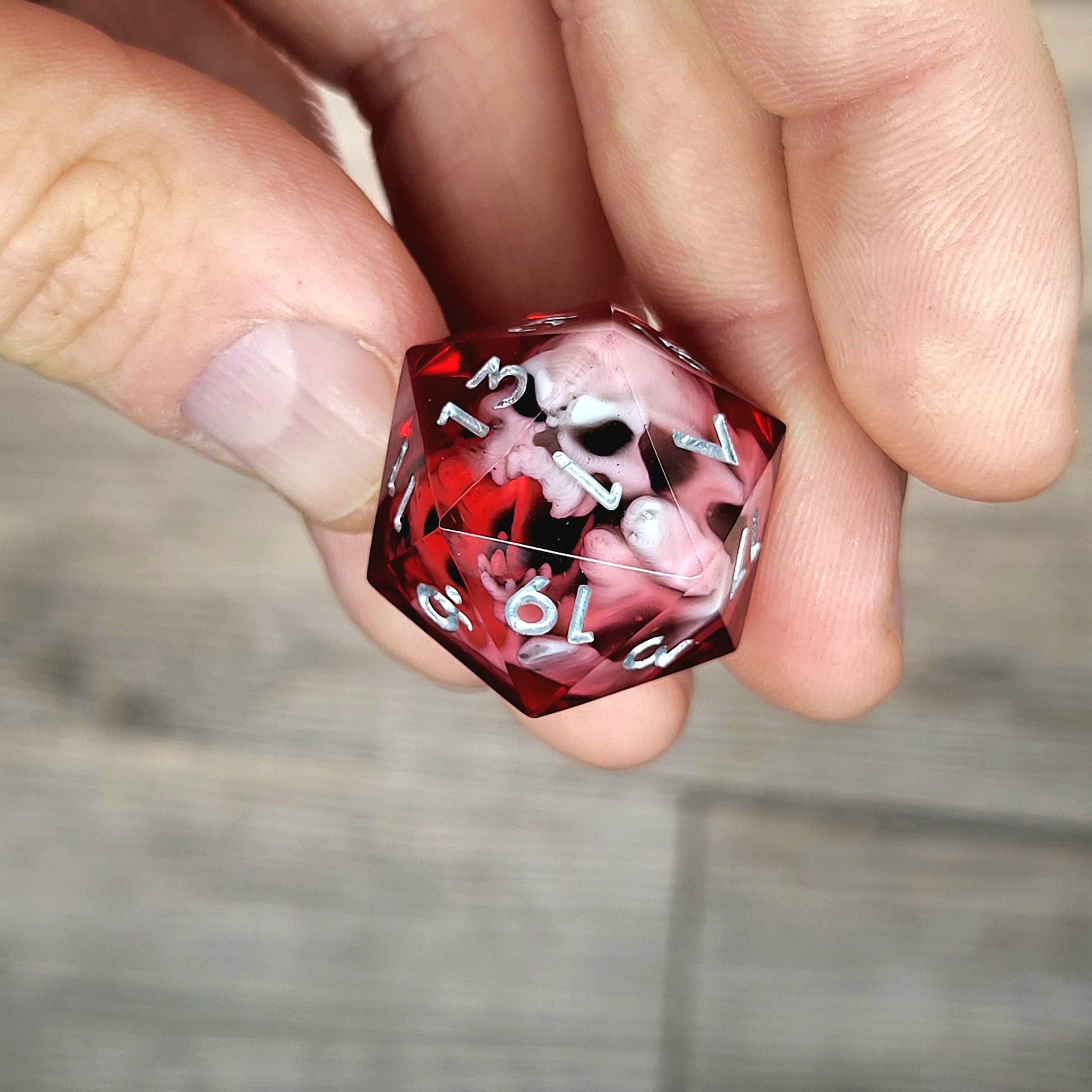 Red resin DnD dice with white skull inside and silver engraved numbers