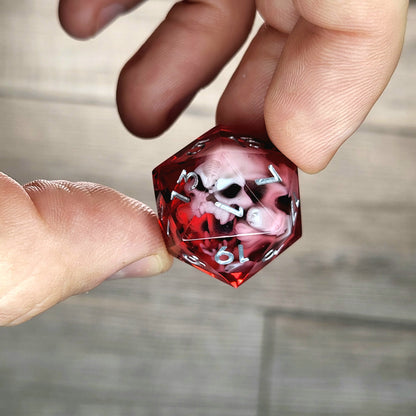 Red resin DnD dice with white skull inside and silver engraved numbers