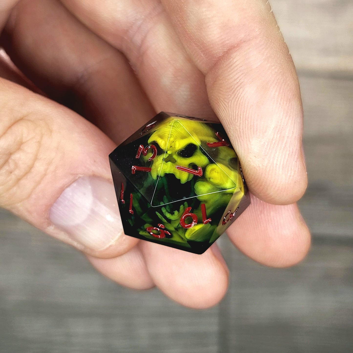 Black resin DnD dice with yellow skull inside and red engraved numbers
