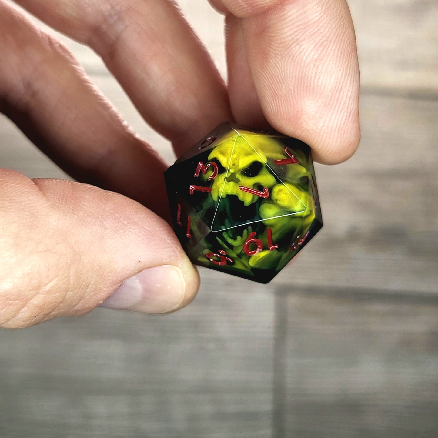 Black resin DnD dice with yellow skull inside and red engraved numbers