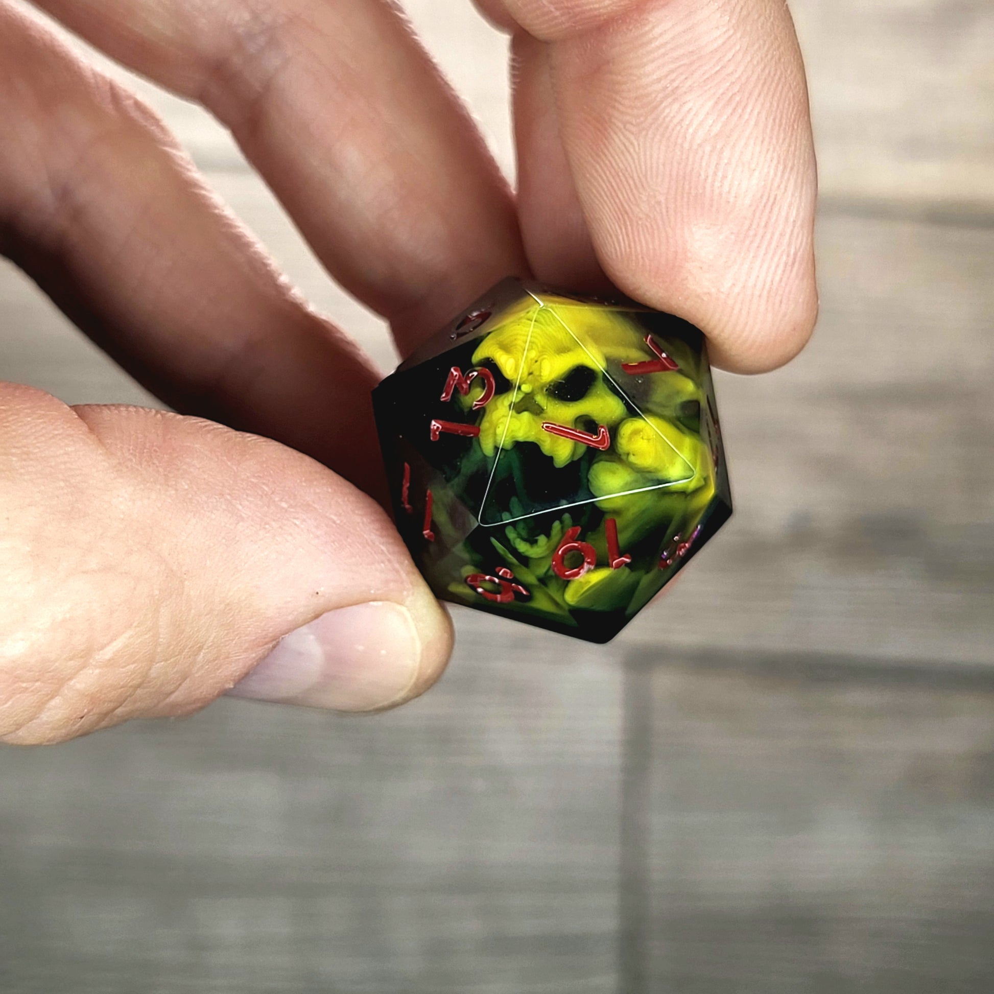 Black resin DnD dice with yellow skull inside and red engraved numbers