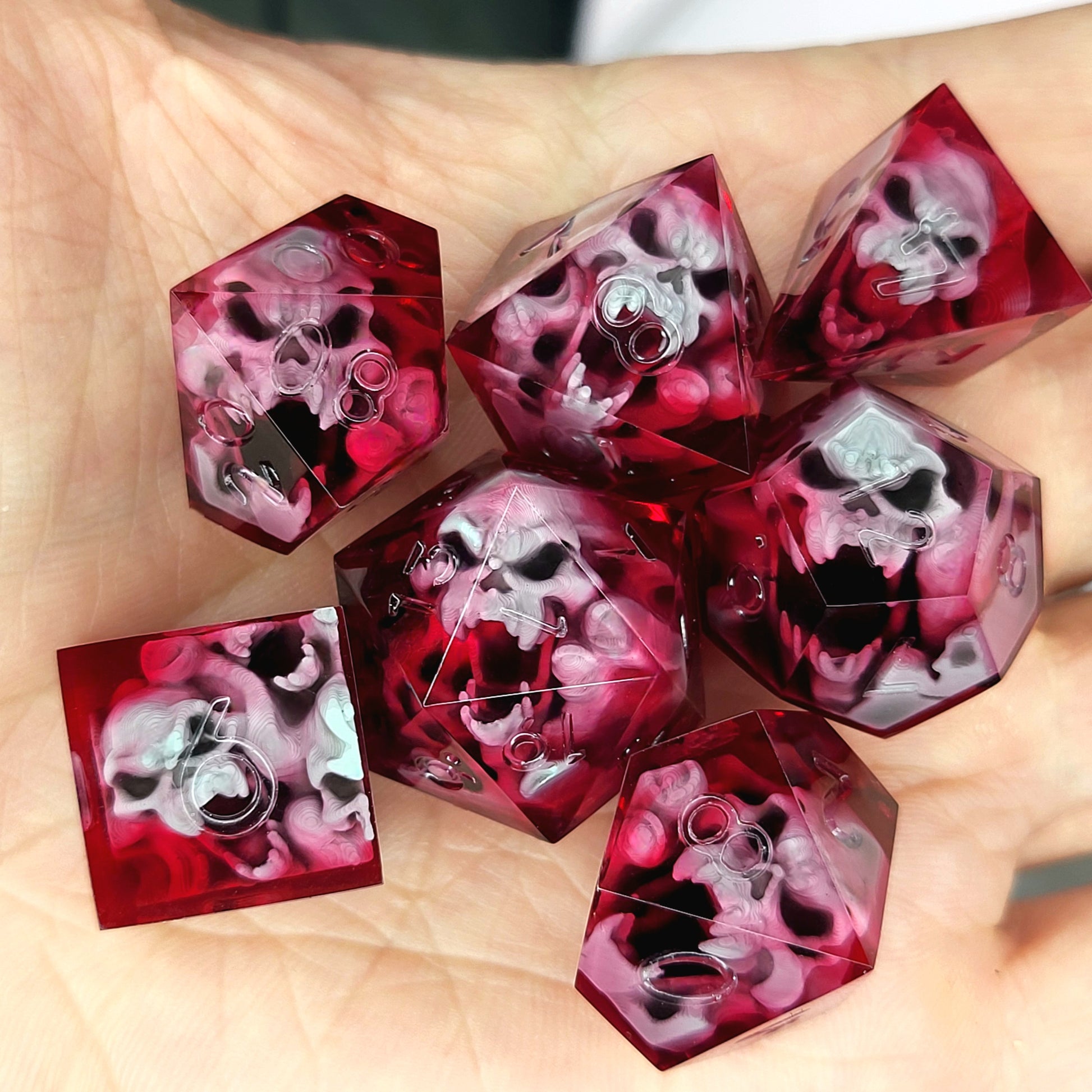Handmade sharp edge resin dice set with floating skull inclusions in transparent crimson red resin