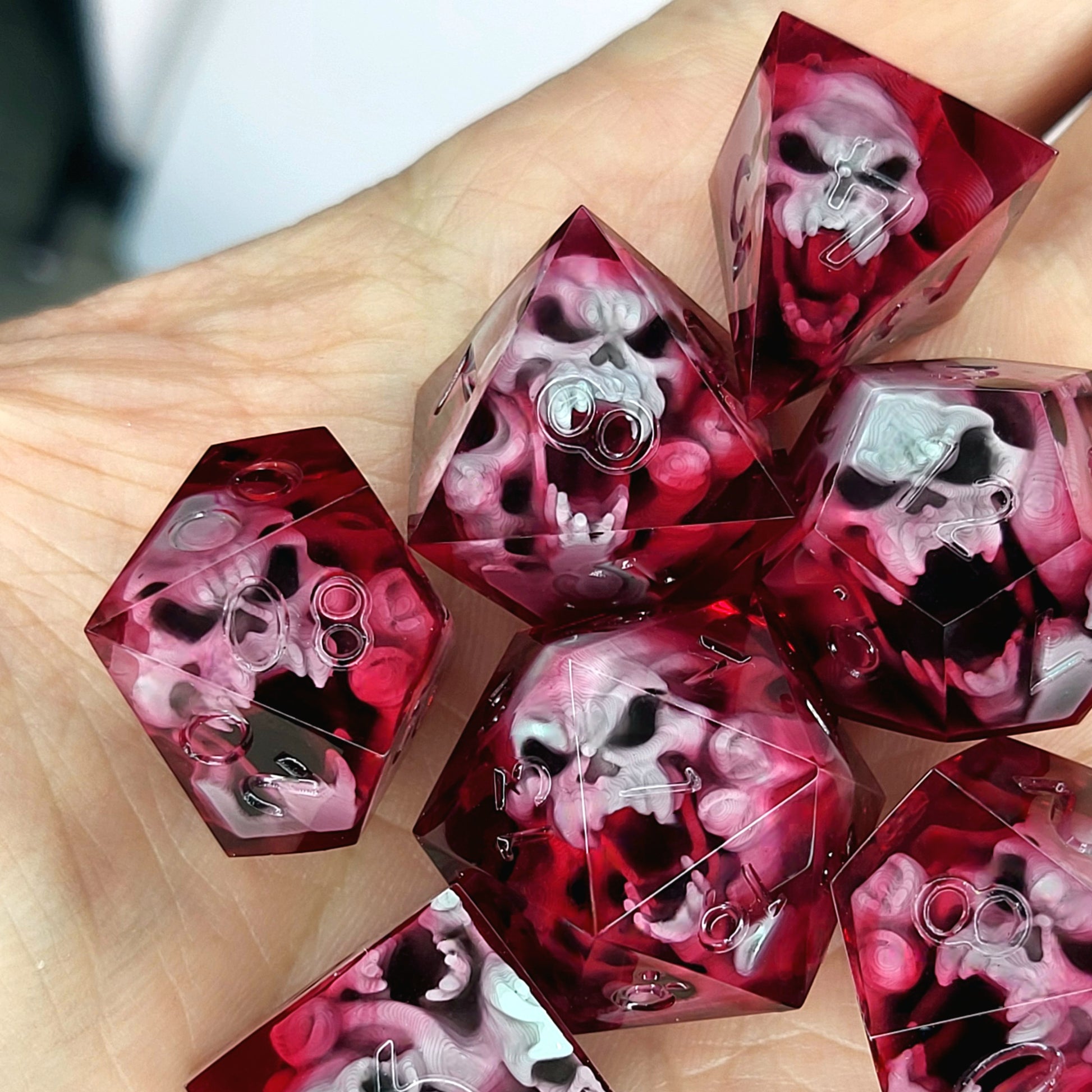 Handmade sharp edge resin dice set with floating skull inclusions in transparent crimson red resin