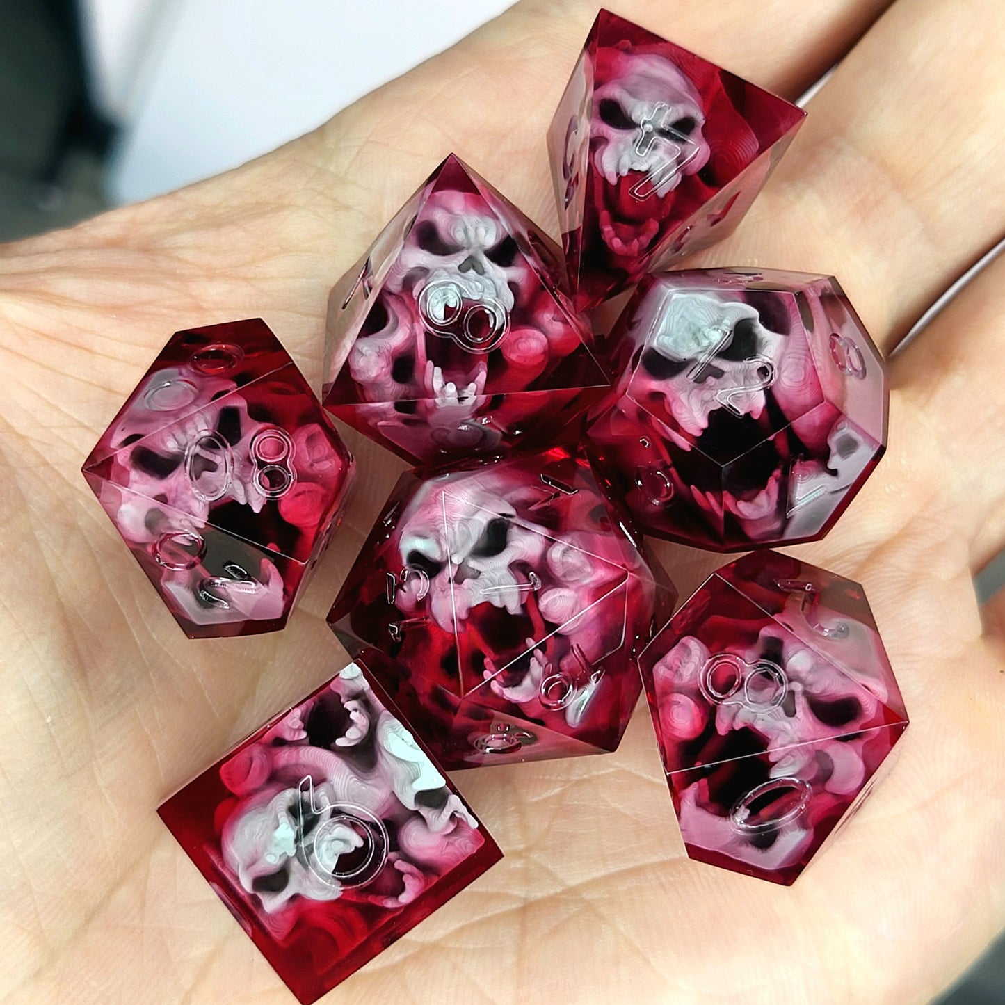 Handmade sharp edge resin dice set with floating skull inclusions in transparent crimson red resin
