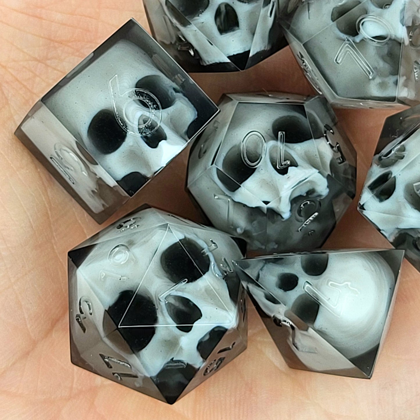 Handmade polyhedral dice set for Dungeons & Dragons (D&D) and tabletop RPGs, crafted in black resin with white skulls embedded inside