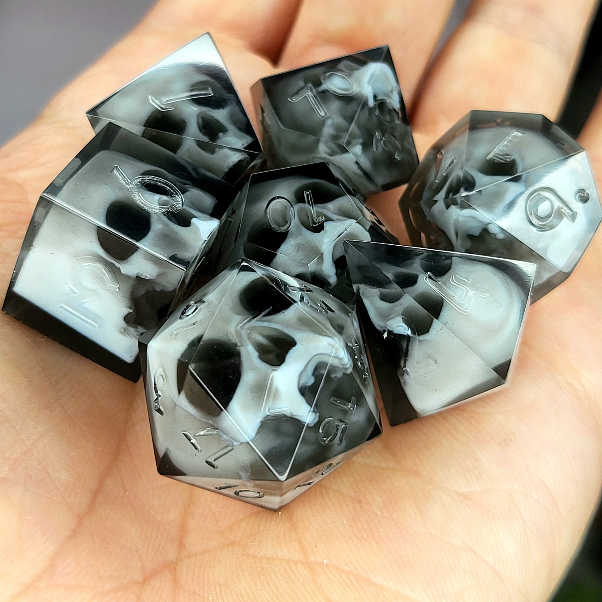 Handmade polyhedral dice set for Dungeons & Dragons (D&D) and tabletop RPGs, crafted in black resin with white skulls embedded inside