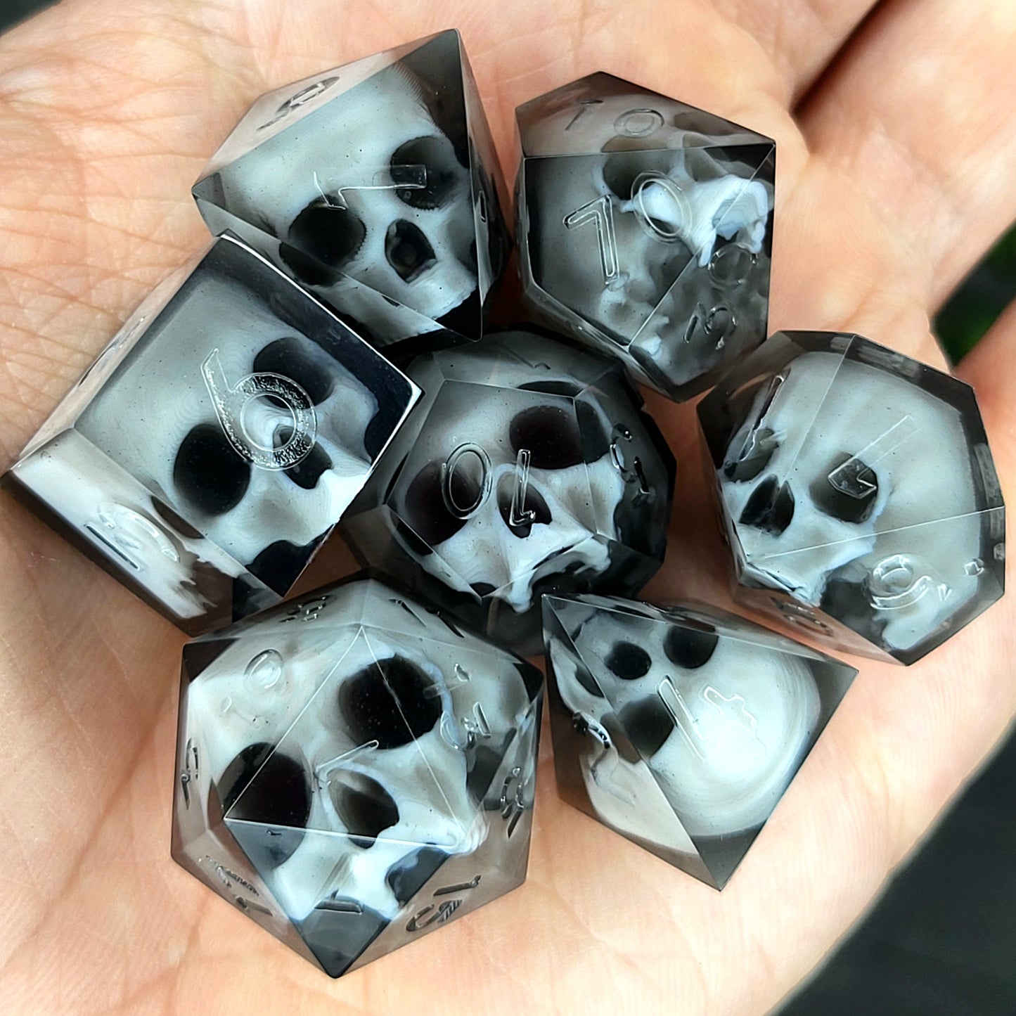 Handmade polyhedral dice set for Dungeons & Dragons (D&D) and tabletop RPGs, crafted in black resin with white skulls embedded inside