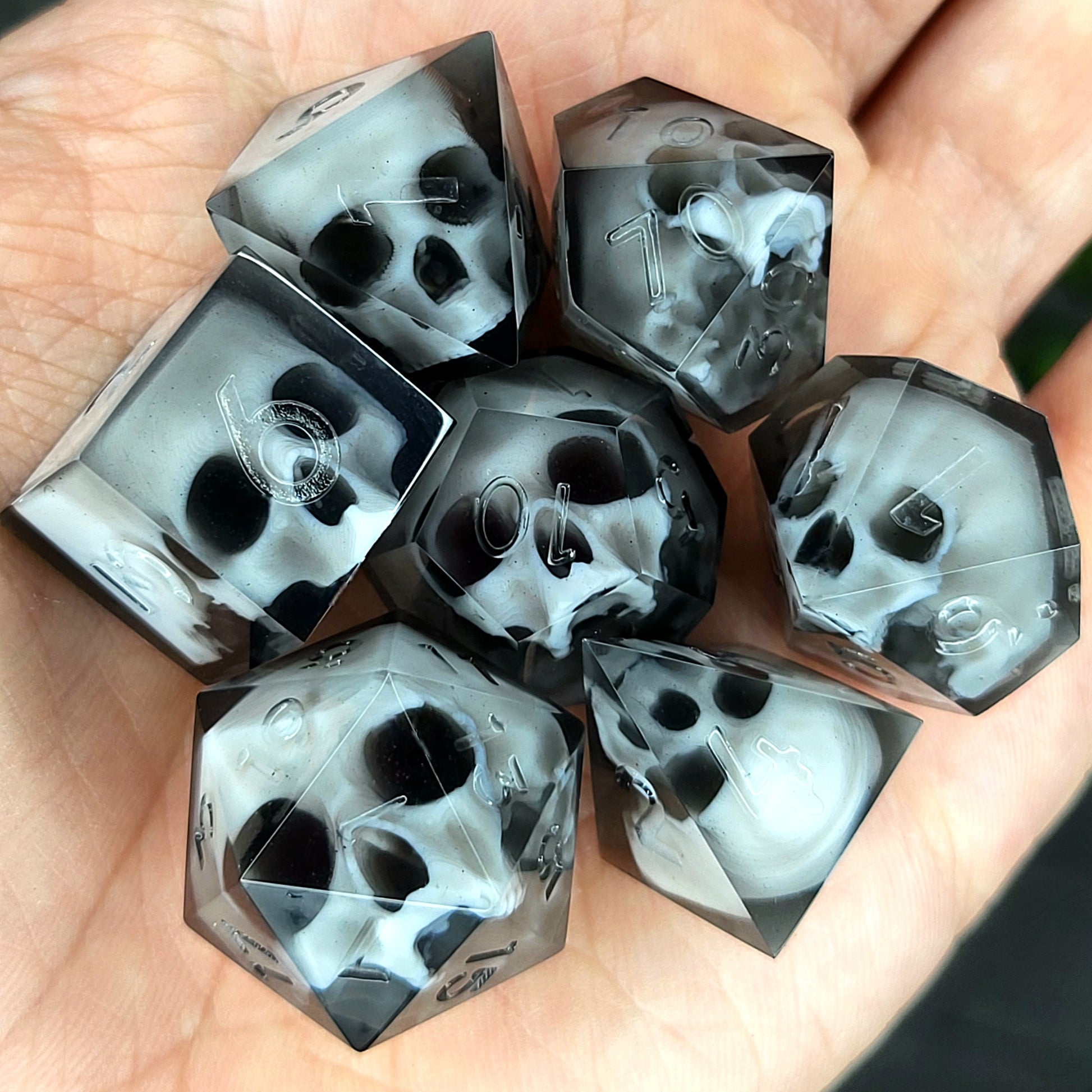 Handmade polyhedral dice set for Dungeons & Dragons (D&D) and tabletop RPGs, crafted in black resin with white skulls embedded inside