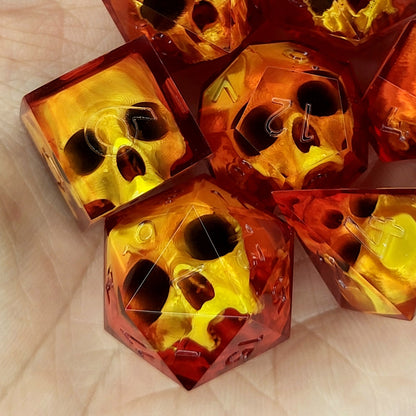 Handmade translucent red resin dice set with embedded skull designs resting in a hand. Gothic RPG polyhedral dice for Dungeons & Dragons and tabletop gaming with dark fantasy aesthetic