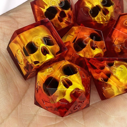 Handmade translucent red resin dice set with embedded skull designs resting in a hand. Gothic RPG polyhedral dice for Dungeons & Dragons and tabletop gaming with dark fantasy aesthetic